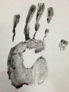 A palm print made with black ink or paint on white paper.